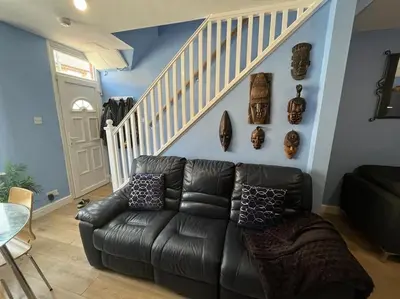 a living room with a black leather couch and a staircase at Charming newly renovated terrace in Liverpool