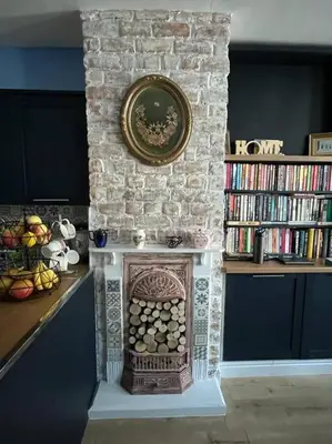a living room with a stone wall with a fireplace at Charming newly renovated terrace in Liverpool