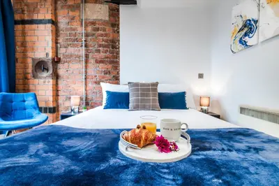 a bed with a blue bedspread with a tray of food on it at Cavern Quarters, Beautiful Two Bedroom City Centre Apartment by Garudy Serviced Apartments in Liverpool