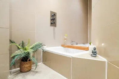 a bathroom with a tub and a plant in it at Cavern Quarters, Beautiful Two Bedroom City Centre Apartment by Garudy Serviced Apartments in Liverpool