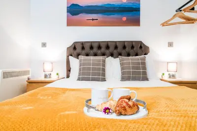 a tray of food on a bed with two mugs at Cavern Quarters, Beautiful Two Bedroom City Centre Apartment by Garudy Serviced Apartments in Liverpool