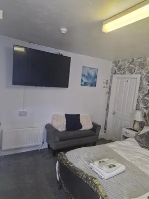 a bedroom with a bed and a couch and a flat screen tv at Rocklea Hotel in Blackpool