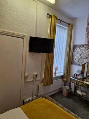 a bedroom with a bed and a television on the wall at Rocklea Hotel in Blackpool