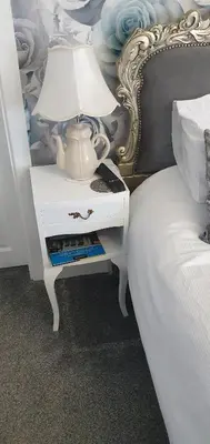 a white nightstand with a lamp on it next to a bed at Rocklea Hotel in Blackpool