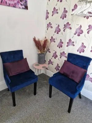 two blue chairs in a room with a wall with purple flowers at Rocklea Hotel in Blackpool