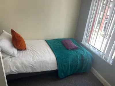 a bed with a green blanket and two pillows on it at Marks Place in Liverpool