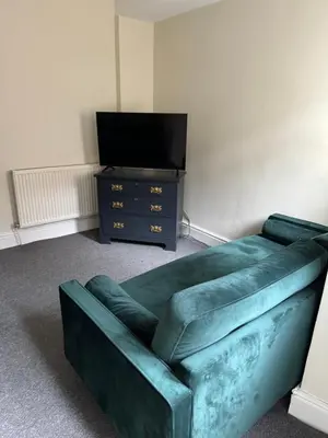 a green couch in a living room with a tv at Marks Place in Liverpool