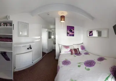 a bedroom with a bed with purple flowers on it at Ardern Hotel in Blackpool