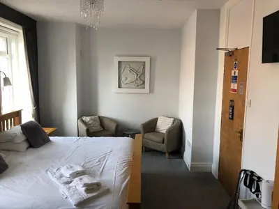 a bedroom with a white bed and a chair at The Fossil Tree Hotel in Blackpool