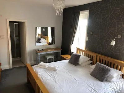 a bedroom with a white bed with a black wall at The Fossil Tree Hotel in Blackpool