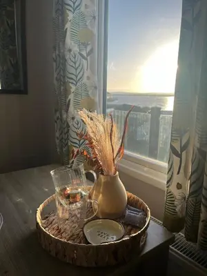 a basket with a vase on a table next to a window at Lake View 92 in Millom