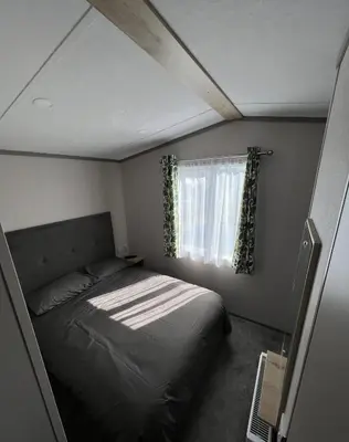 a small bedroom with a bed and a window at Lake View 92 in Millom