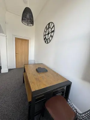 a room with a wooden table and a clock on the wall at Spacious Victorian Birkdale Apartment with Garden in Southport