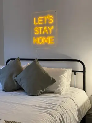 a bed with pillows and a sign that says lets stay home at Spacious Victorian Birkdale Apartment with Garden in Southport
