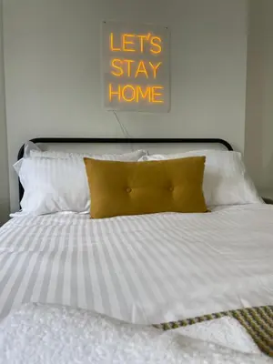 a bed with white sheets and a yellow pillow at Spacious Victorian Birkdale Apartment with Garden in Southport