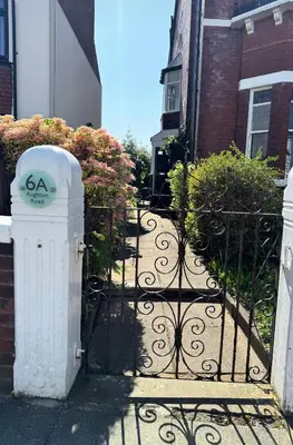 a gate to a house with bushes and flowers at Spacious Victorian Birkdale Apartment with Garden in Southport