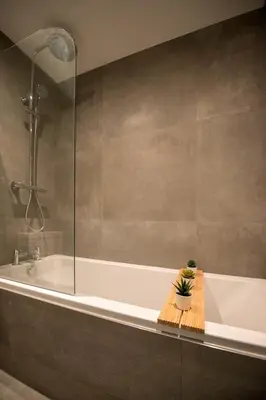 a bathroom with a bath tub with a potted plant at Preston Apartments in Preston
