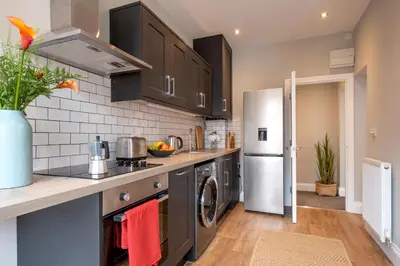 a kitchen with black cabinets and a refrigerator at Preston Apartments in Preston