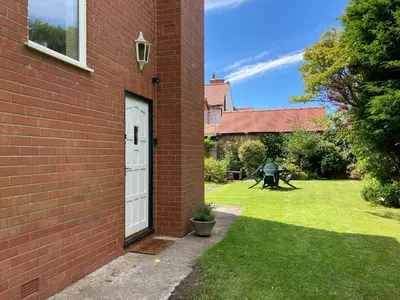 a brick building with a white door and a yard at Fairways in Cleveleys
