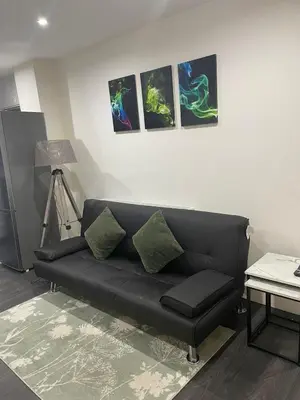 a black couch in a living room with pictures on the wall at Ground Floor Apartment 2, Lynton Apartments in Blackpool