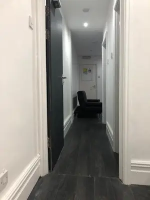 a hallway with a black chair in a room at Ground Floor Apartment 2, Lynton Apartments in Blackpool