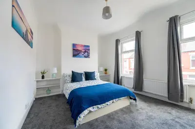 a white bedroom with a blue bed and two windows at Luxury Liverpool Accommodation in Liverpool