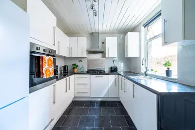 a kitchen with white cabinets and a black tile floor at Luxury Liverpool Accommodation in Liverpool