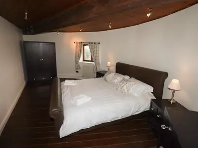 a bedroom with a large bed with white sheets and pillows at Windmill On The Farm in Ormskirk