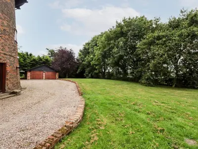 a grassy field next to a brick building with a house at Windmill On The Farm in Ormskirk