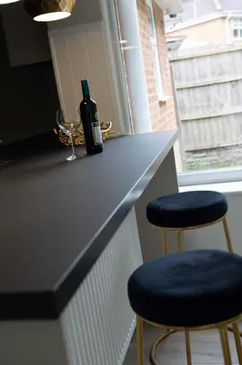 a bottle of wine sitting on a counter with two stools at Woodland House - in Walton le Dale