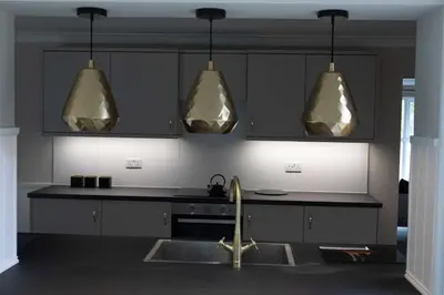 a kitchen with a sink and three pendant lights at Woodland House - in Walton le Dale
