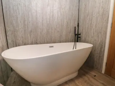 a white bath tub in a bathroom with wooden floors at Ruperts Retreat in Preston