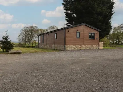 a small wooden building on a gravel parking lot at Ruperts Retreat in Preston