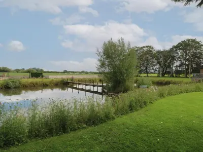 a body of water with a dock in a field at Ruperts Retreat in Preston