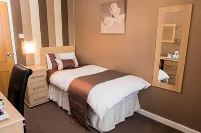 a small bedroom with a bed and a mirror at Trivelles Park Hotel in Preston