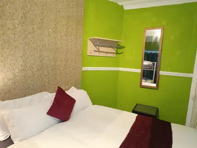a green bedroom with a bed and a mirror at Jewel Of The Sea Hotel in Blackpool