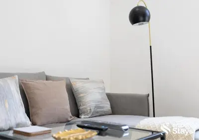 a couch with pillows and a table with a remote control at One Bedroom Apartment At Smooth Stays Short Lets & Serviced Accommodation Preston With Parking Near Train Station in Preston
