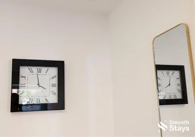 two clocks on a wall in front of a mirror at One Bedroom Apartment At Smooth Stays Short Lets & Serviced Accommodation Preston With Parking Near Train Station in Preston