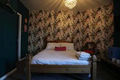 a small bedroom with a bed with floral wallpaper at Ferny House in Blackpool