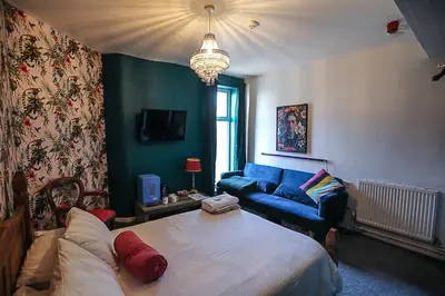 a living room with a bed and a blue couch at Ferny House in Blackpool