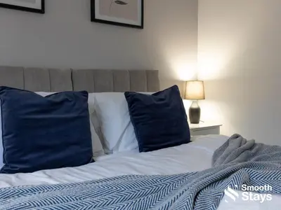 a bed with blue and white pillows in a bedroom at Modern 2 Bed Apartment By Smooth Stays Short Lets & Serviced Accommodation Preston With Parking Near Train Station in Preston