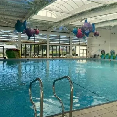 a large swimming pool with blue water in a building at Rydal Retreat Lakeland Holiday Park in Flookburgh