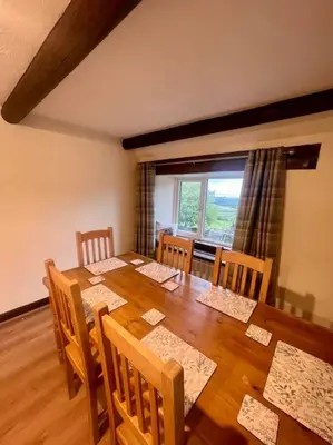 a dining room with a wooden table with chairs and a window at Braffin @ Fellside Farm, Pennington, Ulverston in Pennington