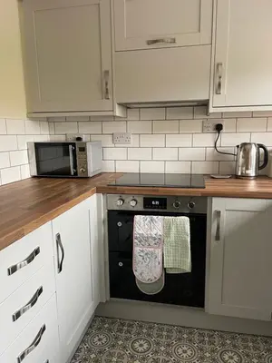 a kitchen with white cabinets and a black oven at Braffin @ Fellside Farm, Pennington, Ulverston in Pennington