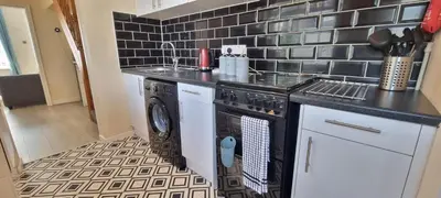 a kitchen with a stove and a washer and dryer at Toffees Townhouse a 2 Bed House in Liverpool 1 Mins walk to Goodison Park in Liverpool