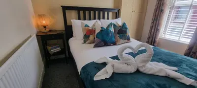 two towel swans are sitting on a bed at Toffees Townhouse a 2 Bed House in Liverpool 1 Mins walk to Goodison Park in Liverpool