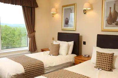 a hotel room with two beds and a window at Higher Trapp Hotel in Burnley