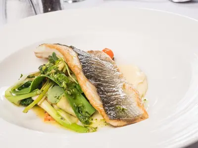 a white plate with a piece of fish and a salad at Higher Trapp Hotel in Burnley