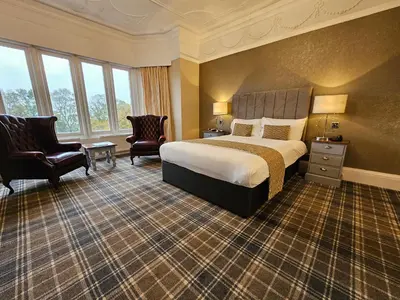 a hotel room with a bed and two chairs at Higher Trapp Hotel in Burnley