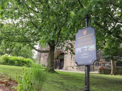 a sign on a pole in front of a building at 5 Castle Hill in Lancaster